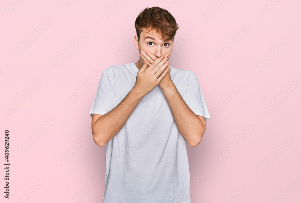Young caucasian man wearing casual white t shirt shocked covering mouth with hands for mistake. secret concept. Young caucasian man wearing casual white t shirt shocked covering mouth with hands for mistake. secret concept.