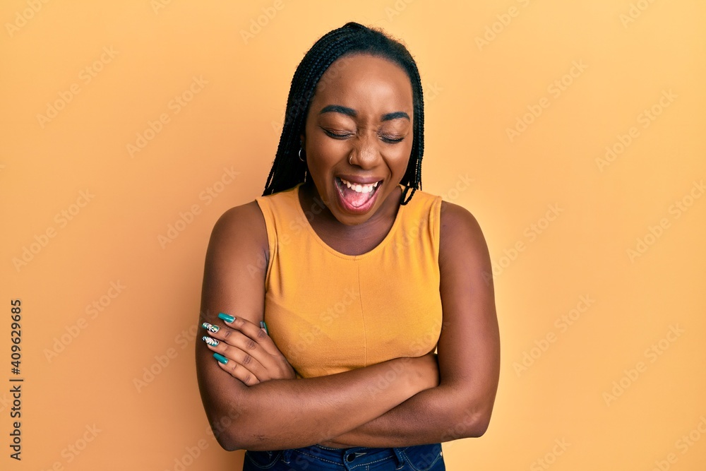 Obraz premium Young african american woman with arms crossed gesture smiling and laughing hard out loud because funny crazy joke.