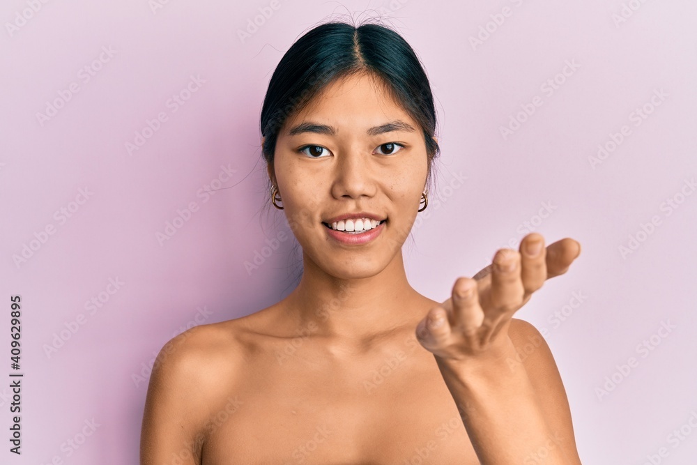 Young chinese woman standing topless showing skin smiling friendly offering handshake as greeting and welcoming. successful business. Young chinese woman standing topless showing skin smiling friendly offering handshake as greeting and welcoming. successful business.