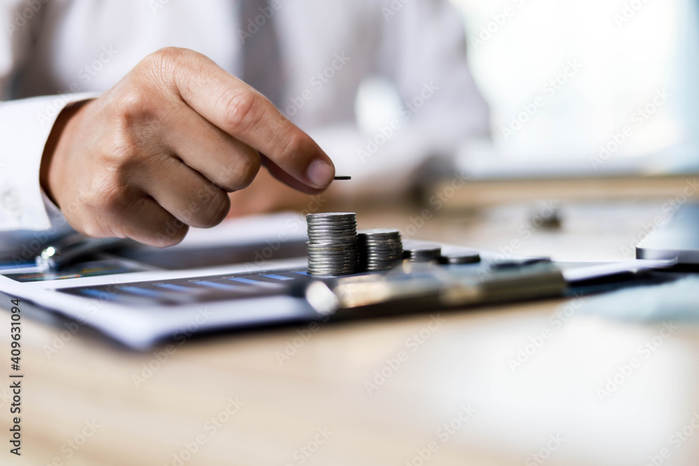 A businessman is putting the coins in order to keep them neatly, he will invest his savings for growth, the idea of saving money to grow. A businessman is putting the coins in order to keep them neatly, he will invest his savings for growth, the idea of saving money to grow.