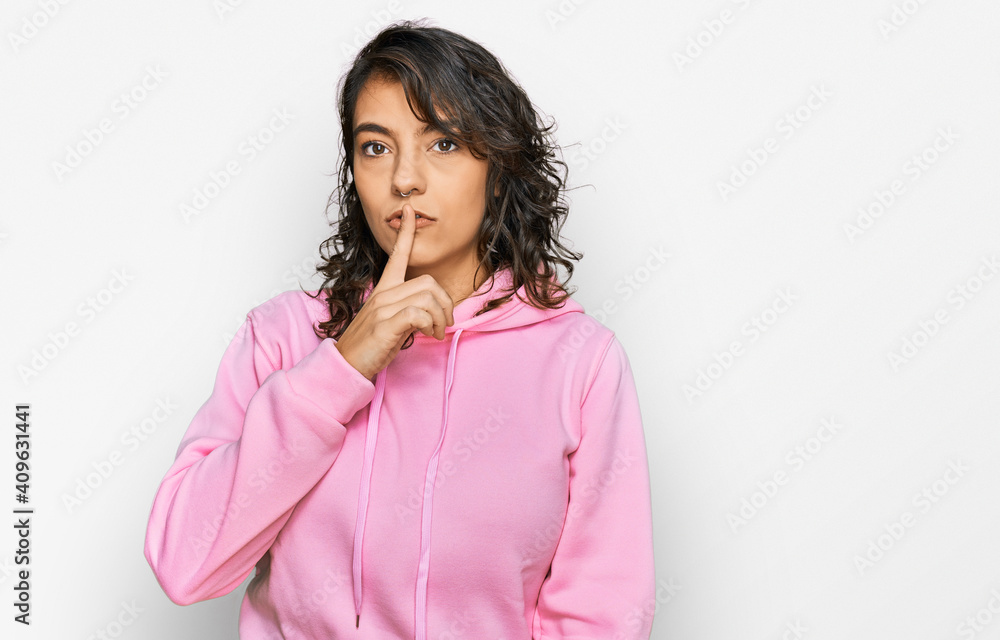 Young hispanic woman wearing casual sweatshirt asking to be quiet with finger on lips. silence and secret concept. Young hispanic woman wearing casual sweatshirt asking to be quiet with finger on lips. silence and secret concept.