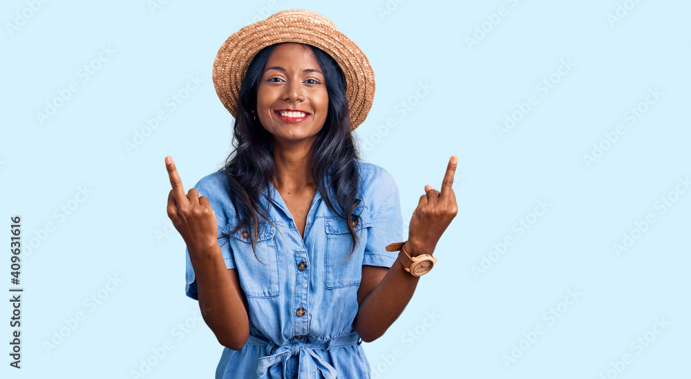 Young indian girl wearing summer hat showing middle finger doing fuck you bad expression, provocation and rude attitude. screaming excited