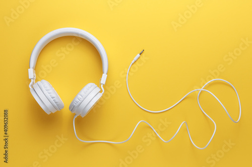 Modern white headphone on yellow background. Music concept.