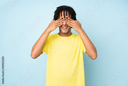 Young african american man isolated on blue background covering eyes by hands