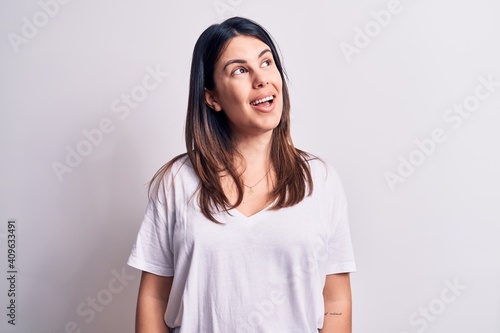 Young beautiful brunette woman wearing casual t-shirt standing over isolated white background looking to side, relax profile pose with natural face and confident smile.