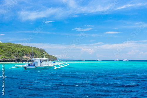 Tropical lagoon of Sumilon island, Philippines. Traditional filipino banca boat in azure crystal clear water.