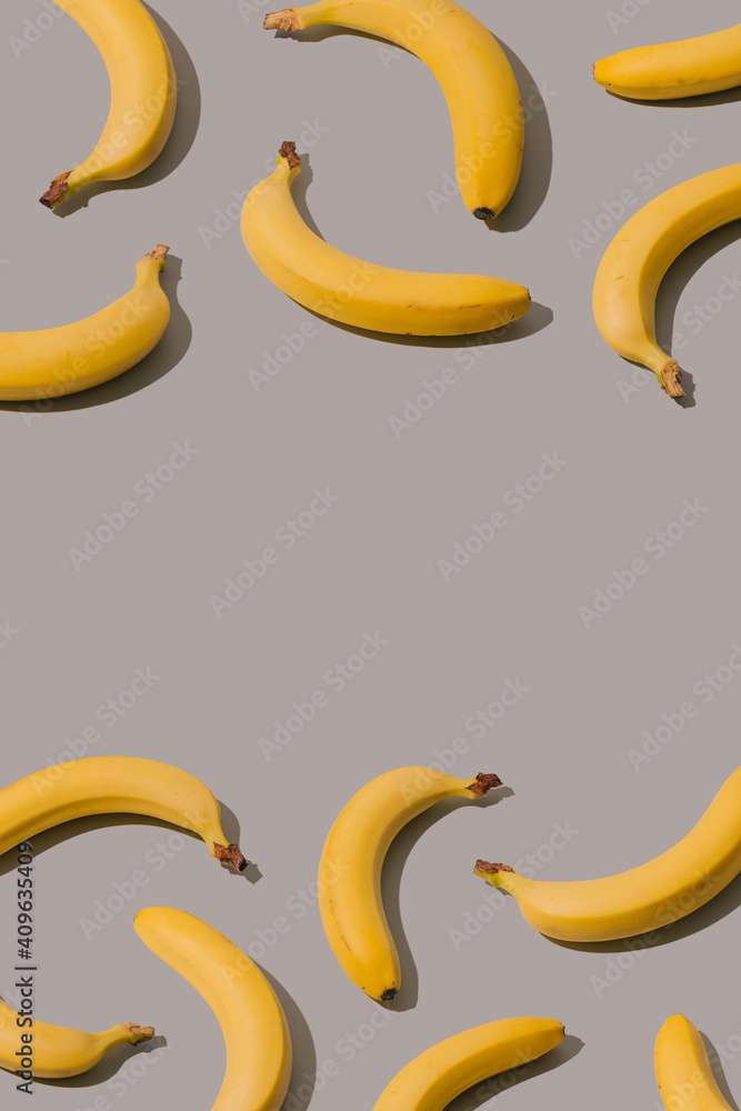 Creative pattern made with yellow bananas on a gray background. Minimal abstract aesthetic idea.