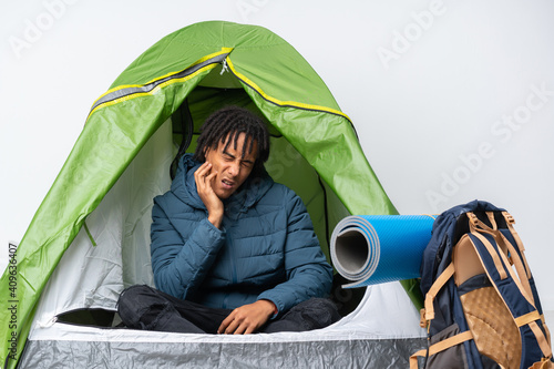 Young african american man inside a camping green tent with toothache