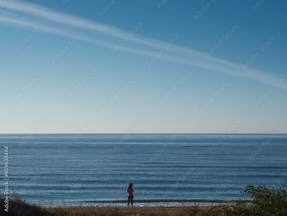 Unreconognizable person silhouette walking on the beach. Mediterranean sea and blue sky