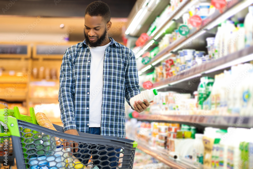 African Man On Grocery Shopping In Supermarket Choosing Dairy Products