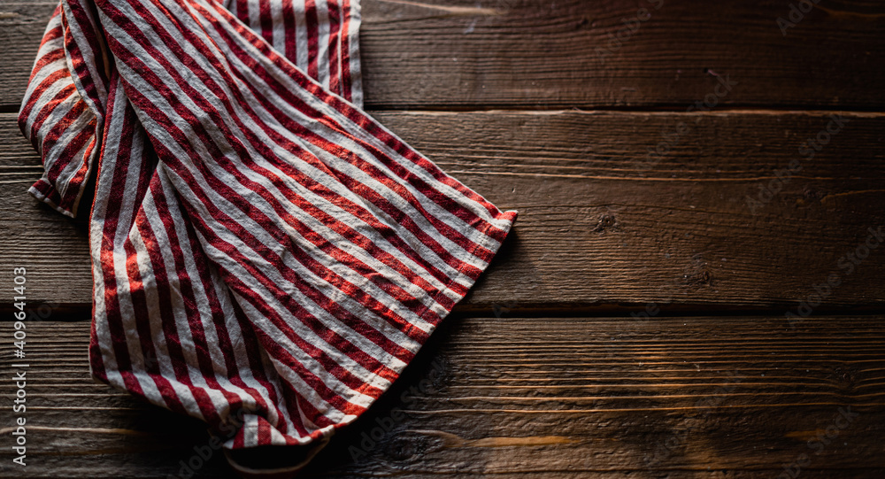a towel in red and white stripes, lying on a table made of wood with a texture, daylight falls from the window. copy space a towel in red and white stripes, lying on a table made of wood with a texture, daylight falls from the window. copy space