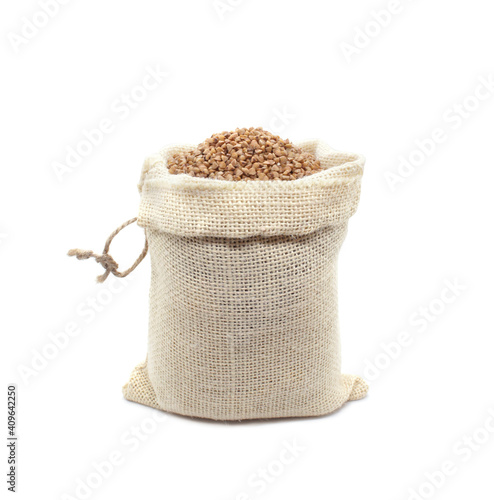 Buckwheat in burlap bag isolated on white background. Raw buckwheat groats in open bag. Close-up.