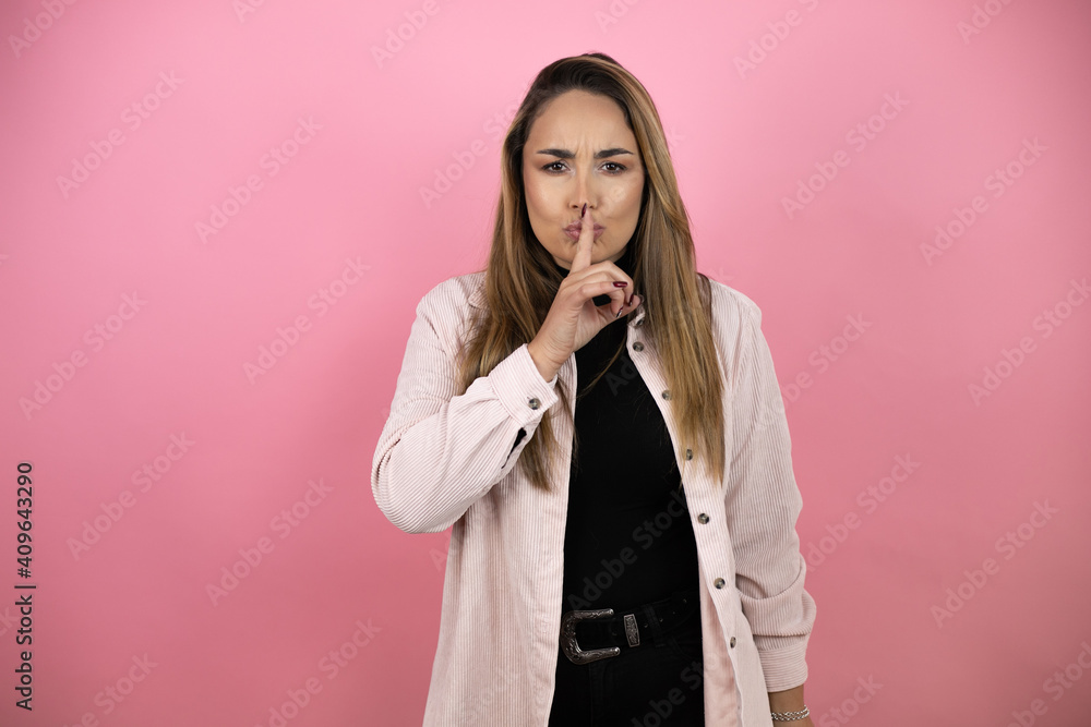 Young beautiful blonde woman with long hair standing over pink background asking to be quiet with finger on lips. Silence and secret concept. Young beautiful blonde woman with long hair standing over pink background asking to be quiet with finger on lips. Silence and secret concept.