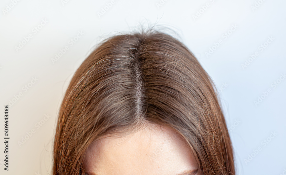 A woman's head with a parting of gray hair. A woman's head with a parting of gray hair.