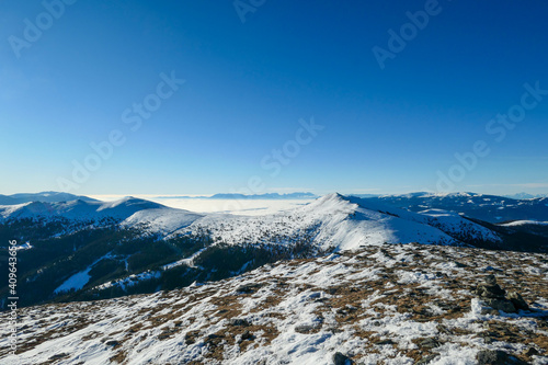 A drone shot of snow capped Alps in the region of Speikkogel in Austrian Alps. The whole are is covered with snow. Many mountain chains in the back. Thick fog in the valley. Winter outdoor activity. photo