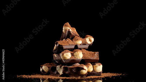 chocolate. stack of chocolate bar with nuts and cocoa powder on black background. dark chocolate with nuts. confectionery concept