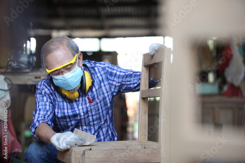 Carpenter, joiner is working in the workshop. Man at work on wood.Image of mature carpenter in the workshop,furniture making concept.