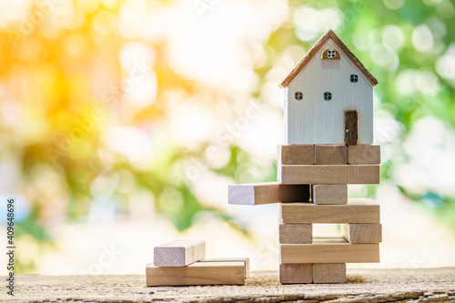 Foto Stacking wooden sticks with growing on by steps and home is destinations on sunlight background, Saving money or loan for buy insurance of real estate protection concept