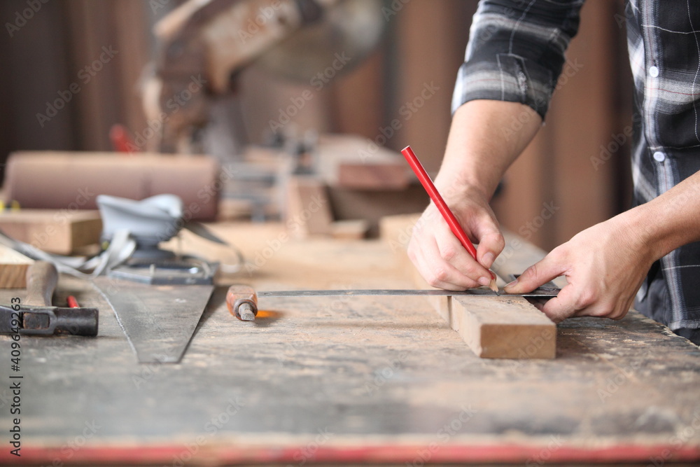 Carpenter, joiner is working in the workshop. Man at work on wood.Image of mature carpenter in the workshop,furniture making concept. Carpenter, joiner is working in the workshop. Man at work on wood.Image of mature carpenter in the workshop,furniture making concept.