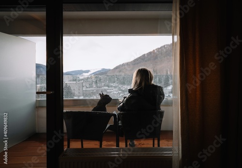 French bulldog dog and woman sitting in balcony in rainy day