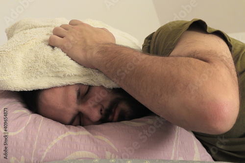 Fotografija man covering his ears with pillow at the morning