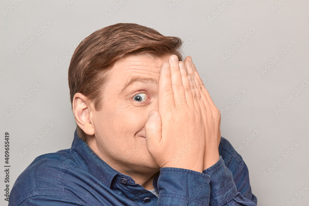 Portrait of happy man looking with one eye at something interesting Portrait of happy man looking with one eye at something interesting