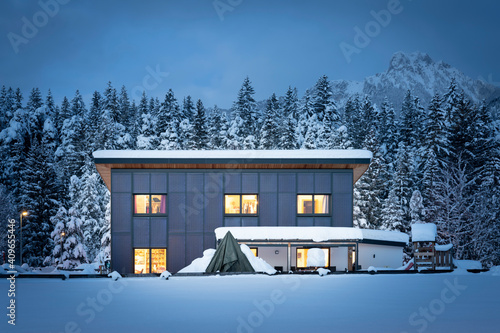 Frontal view of a single-family house with a solar thermal facade for sustainable and renewable heating and hot water energy at night in winter