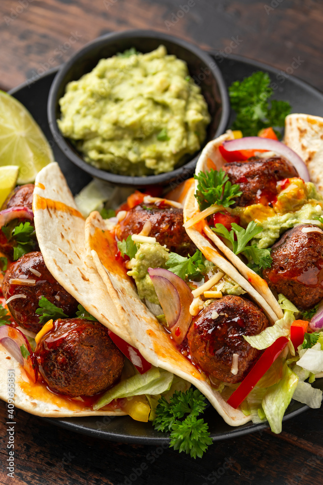 Meat free beetroot and pea protein meatballs taco wraps with avocado guacamole, sweet chilli sauce and lime wedges Meat free beetroot and pea protein meatballs taco wraps with avocado guacamole, sweet chilli sauce and lime wedges