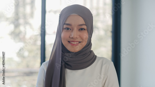 Portrait of successful beautiful executive businesswoman casual wear looking at camera and smile, happy in modern office workplace. Young Asia muslim lady stand relax in contemporary coworking space.