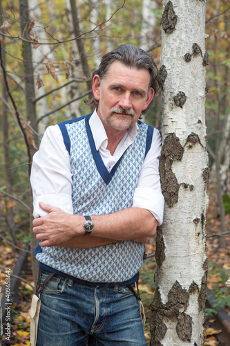 portrait of handsome man in his 50s standing in the forest