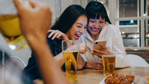 Photography Group of happy tourist young Asia friend using mobile phone, drink alcohol beer and having hangout party in night club at Khao San Road