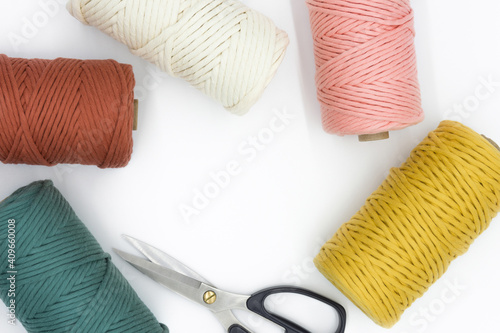 Close-up view of the colorful single strand cotton cords and scissor for macrame DIY handcraft isolated on white background. photo