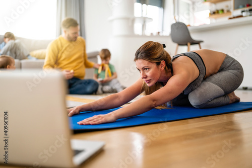 Wallpaper Mural Young woman, mother exercising at home in living room, father playing with kids in background. Torontodigital.ca
