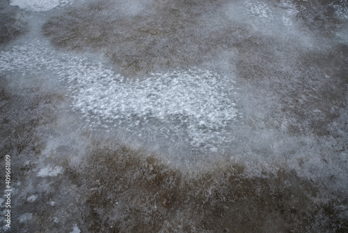 Texture of ice and frozen sand on the shore of the lake.