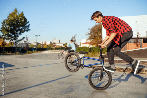 Two male bmx bikers doing tricks in skatepark