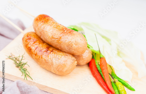 Thai style sausage, made from glass noodles, lean pork with garlic, pepper, coriander seed, seasoning sauce, grilled. placed on a plate with fresh cauliflower and chili. Thai street food