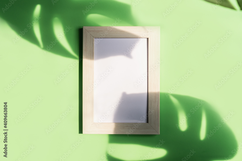 Empty picture frame with shadow of tropical green leave on color background with copy space, Top view Empty picture frame with shadow of tropical green leave on color background with copy space, Top view