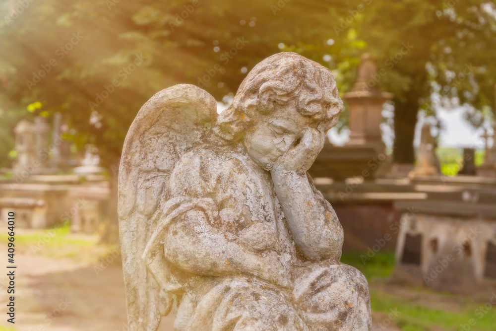 Little angel crying. Stone statue. Sunlight effect (concept children's mortality)
