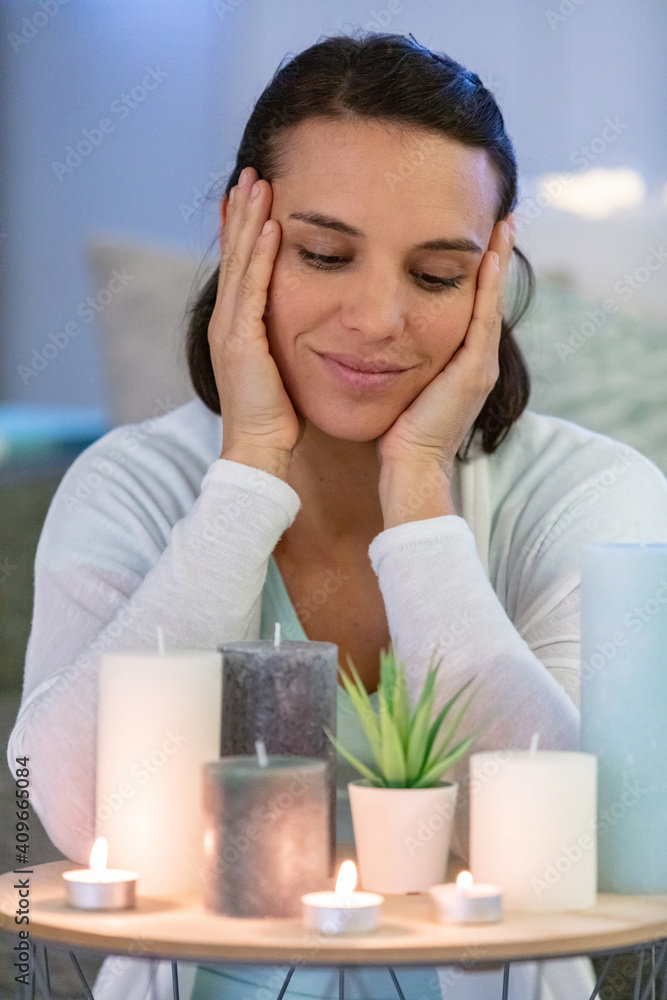 woman looking lovingly at selection of candles on her table woman looking lovingly at selection of candles on her table