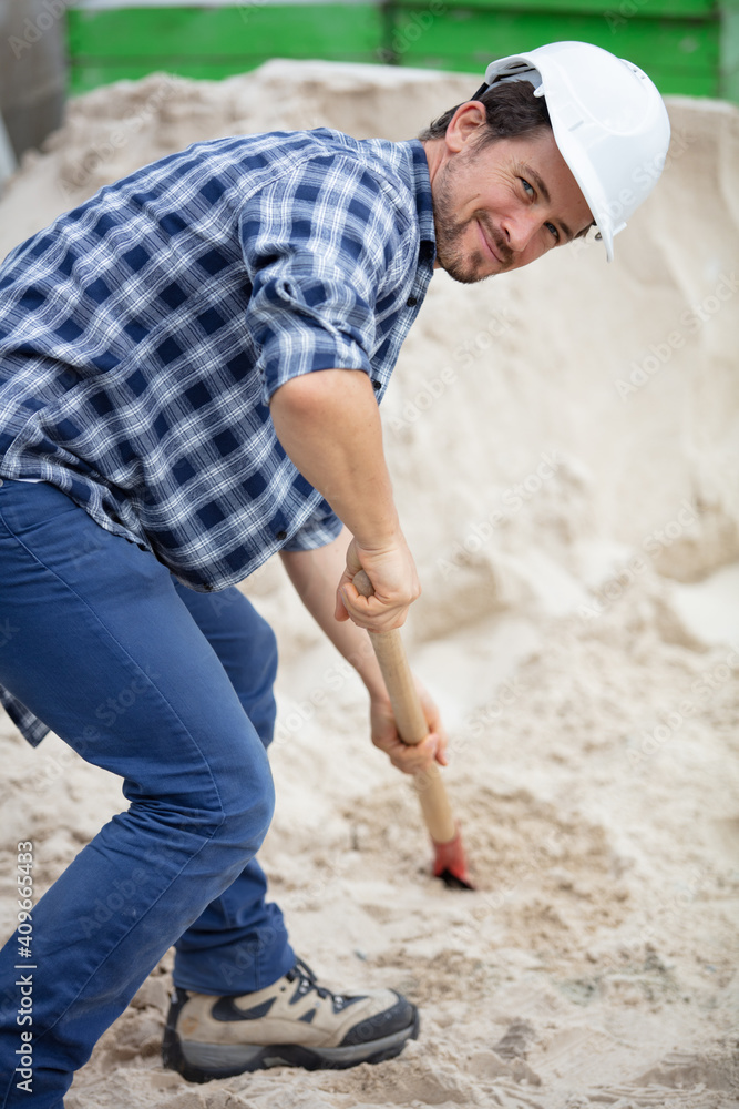 male manual worker shovelling sand
