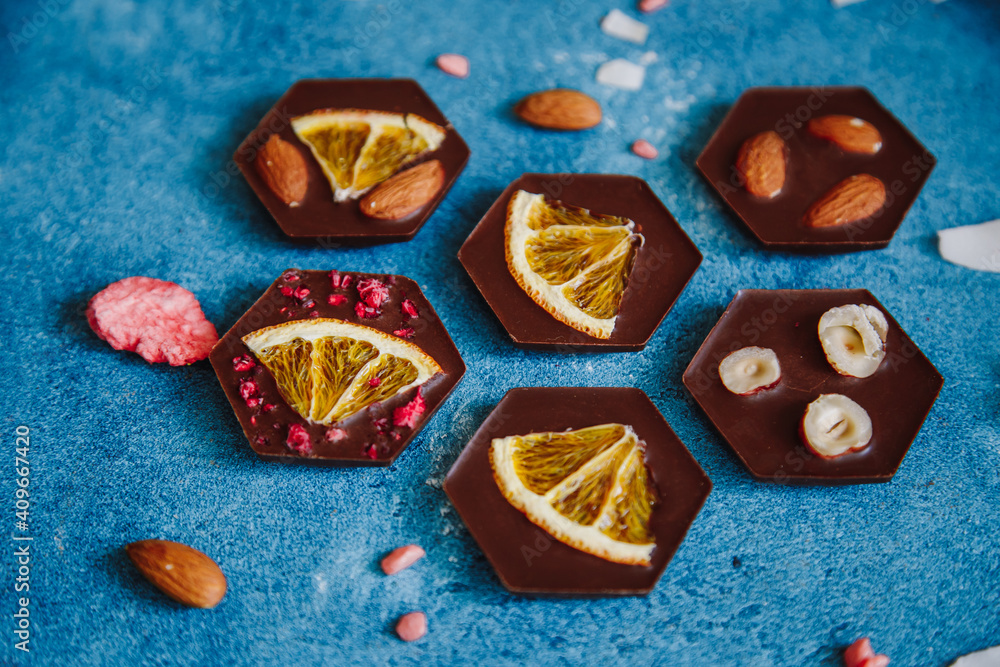 Diet dark chocolate without sugar based on cocoa and stevia with the addition of freeze-dried berries, nuts and fruits. Top view on blue background Diet dark chocolate without sugar based on cocoa and stevia with the addition of freeze-dried berries, nuts and fruits. Top view on blue background