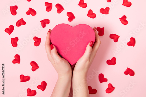 Female hands are holding a large pink heart. Valentine's day concept, place for text.