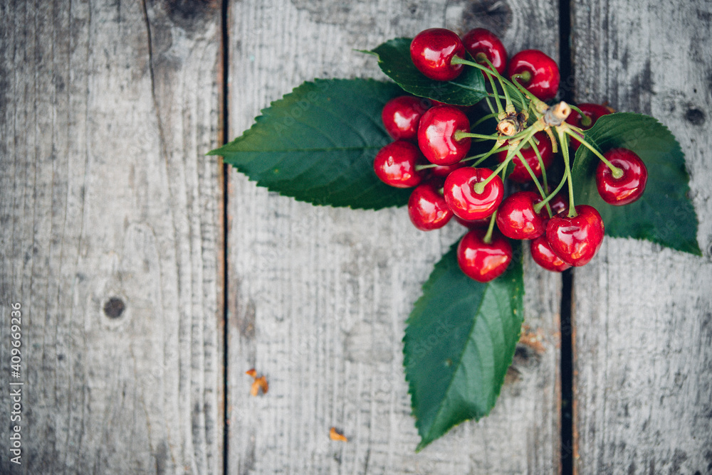 fresh red cherries on an old wooden table with green leaves, rustic style fresh red cherries on an old wooden table with green leaves, rustic style
