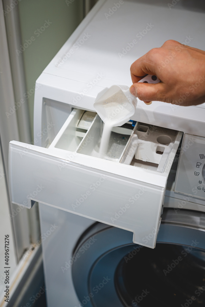 hand pouring detergent powder into the drawer of a washing machine hand pouring detergent powder into the drawer of a washing machine
