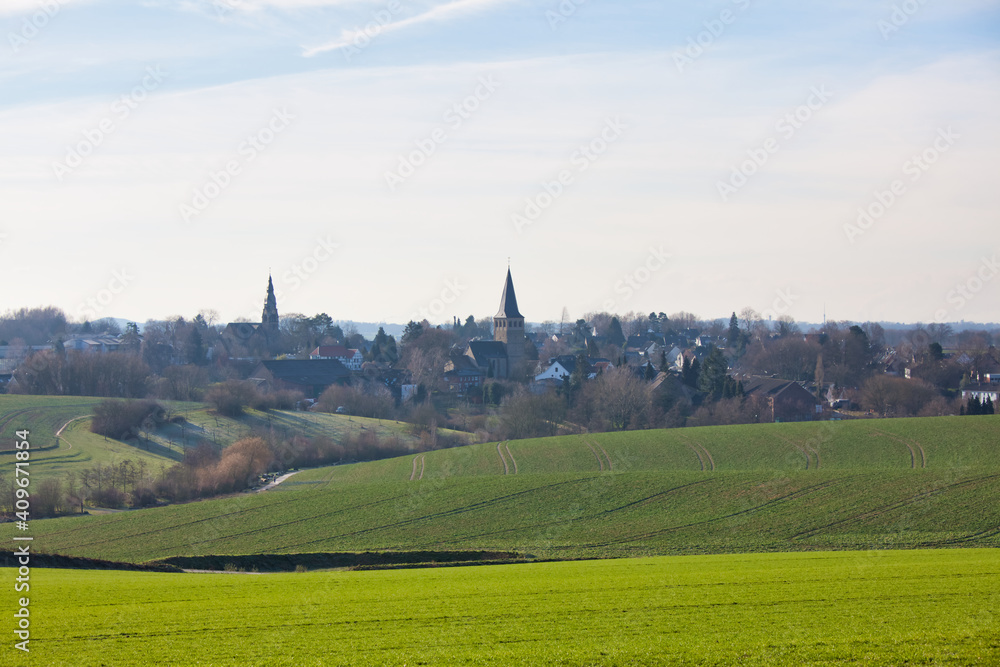 the catholic and protestant church of homberg in winter with sun and green field	