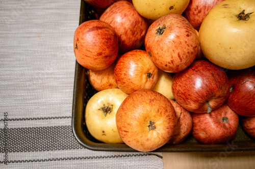 Basket with natural red and yellow apples on table.