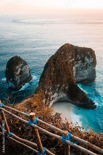 Woman in white shirt and blue denim jeans standing on brown wooden ladder near brown rock photo