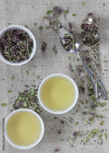 Thyme dried flower herbal tea in a white chinese cups on linen textile with blossoms and spoon nearby  closeup  copy space  flat lay  from above overhead top view  healthy herbal teas concept