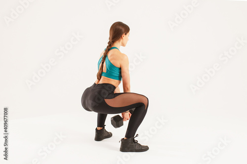 athletic sportswoman doing squats exercise with dumbbells isolated on white background