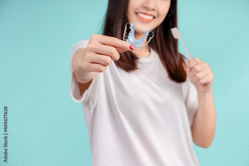 Dental Beautiful smiling of young asian woman with retainer braces and toothbrush for white teeth increase confidence for healthy on blue background isolated, Happiness teenager facial expression. Dental Beautiful smiling of young asian woman with retainer braces and toothbrush for white teeth increase confidence for healthy on blue background isolated, Happiness teenager facial expression.